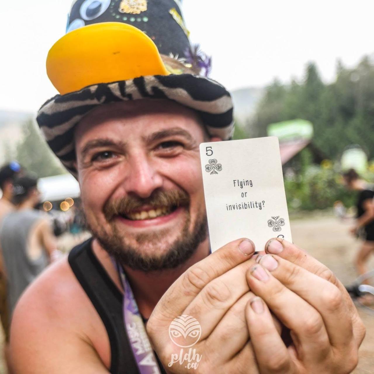 Gabriel Mccay smiling broadly at the camera while holding a card forward, wearing a novelty top hat with a yellow duck bill
